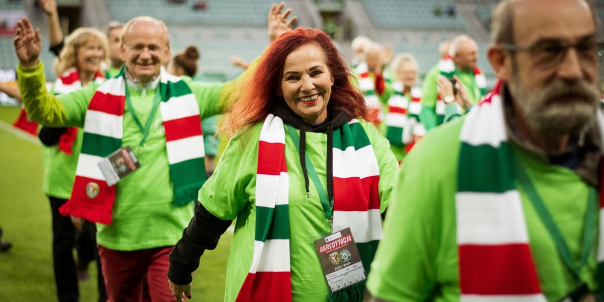 Eskorta seniorów dla piłkarzy Śląska Wrocław na Tarczyński Arenie. Wszyscy mają zielone koszulki i biało-czerwono-zielone szaliki