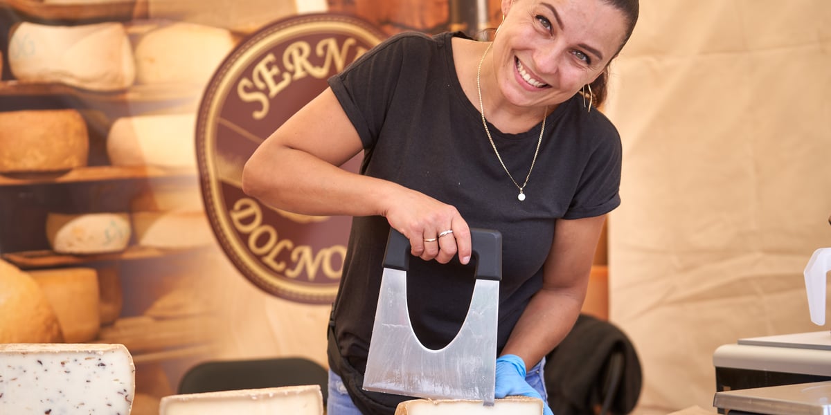 Wrocławska Feta - Festiwal Wina, Piwa i Sera 2023 w Rynku. Na zdjęciu widać kobietę, która kroi ser 