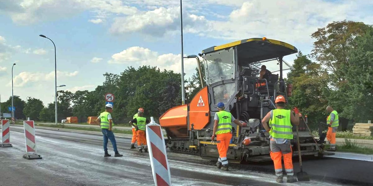 Na ul. Kosmonautów trwa układanie asfaltu. Na zdjęciu są pracownicy oraz specjalna maszyna.