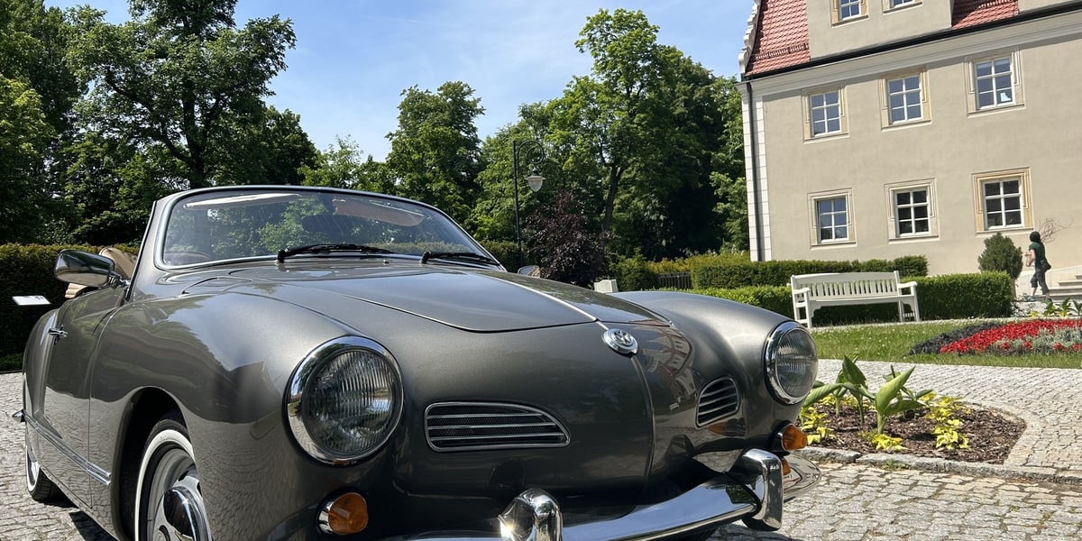 Zielony samochód marki Volkswagen typu cabrio na tle Zamku Topacz