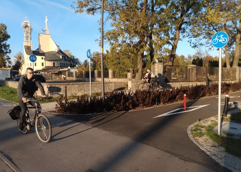 Z lewej młody mężczyzna w czarnym stroju na rowerze
