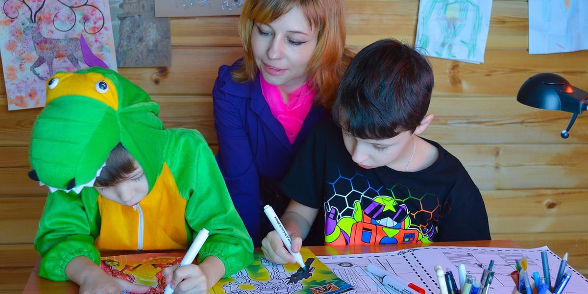Kobieta z bawiącymi się dziećmi przy stole. Zdjęcie ilustracyjne