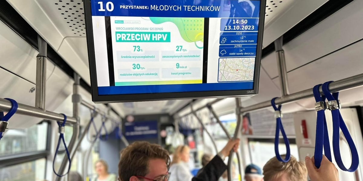 Pasażerowie w tramwaju 10, na wyświetlaczu: grafika promująca szczepienia przeciwko HPV