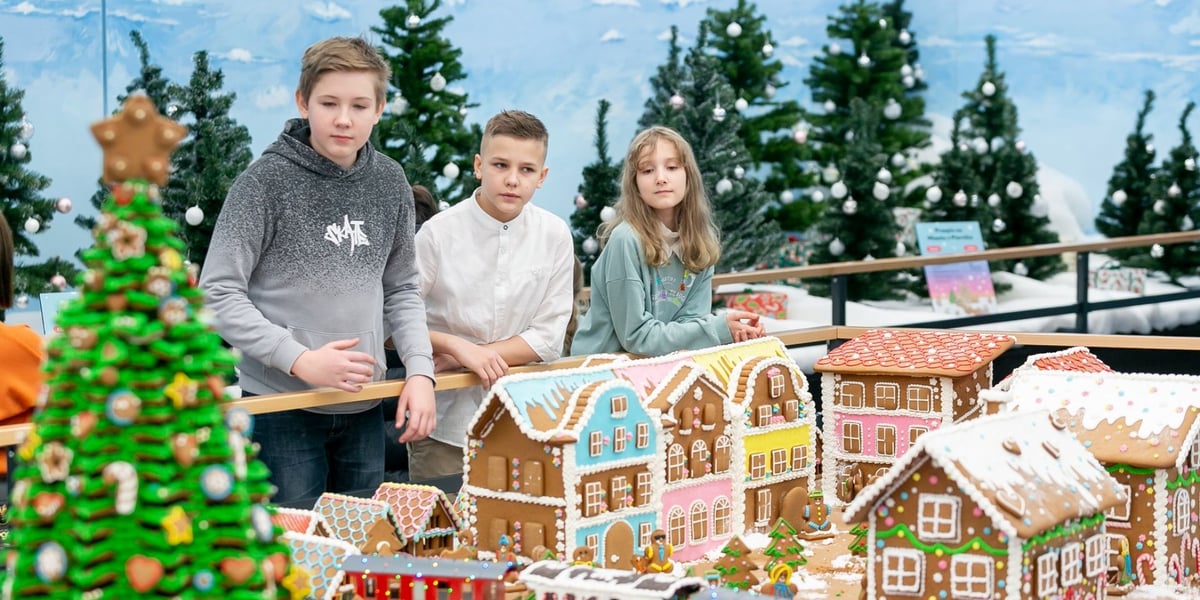 Miasto z Piernika w Kolejkowie. Widać budynki, choinki oraz trójkę zwiedzających dzieci - dwóch chłopców i dziewczynkę