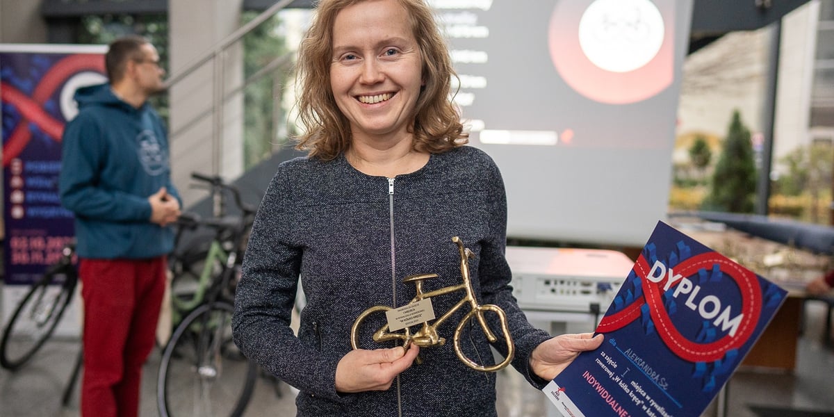 Kobieta z dyplomem i statuetką w kształcie roweru; AleksandraSZ zwyciężczyni rywalizacji "W kółko kręcę" edycja jesień 2023 