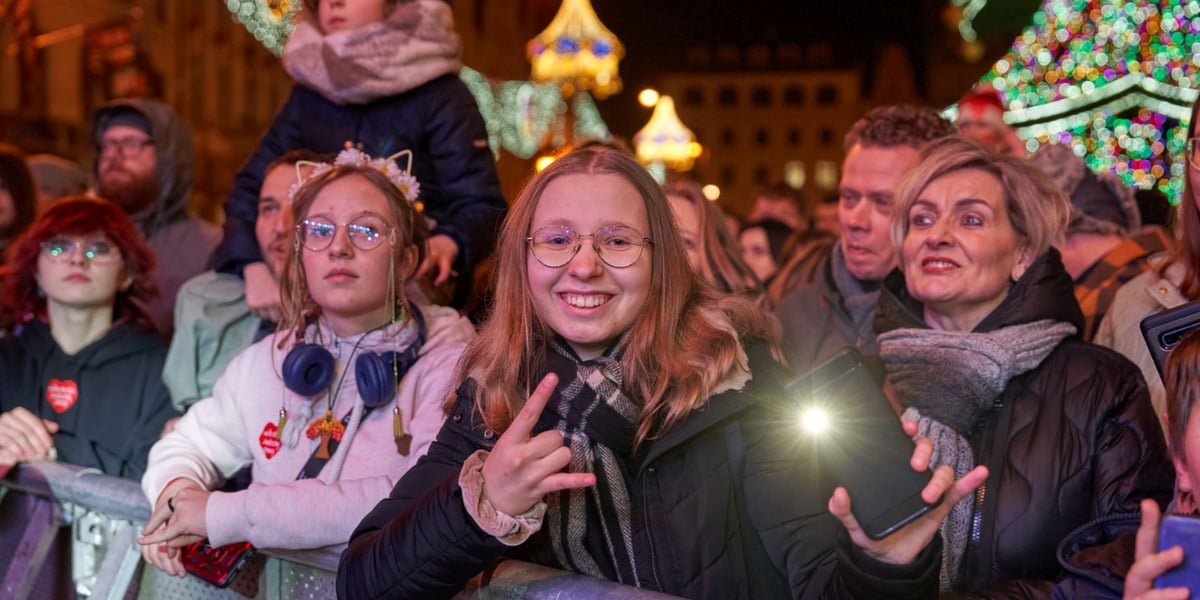 Światełko do Nieba w Rynku podczas Finału WOŚP. Publiczność przed sceną. Na pierwszym planie młoda dziewczyna z telefonem
