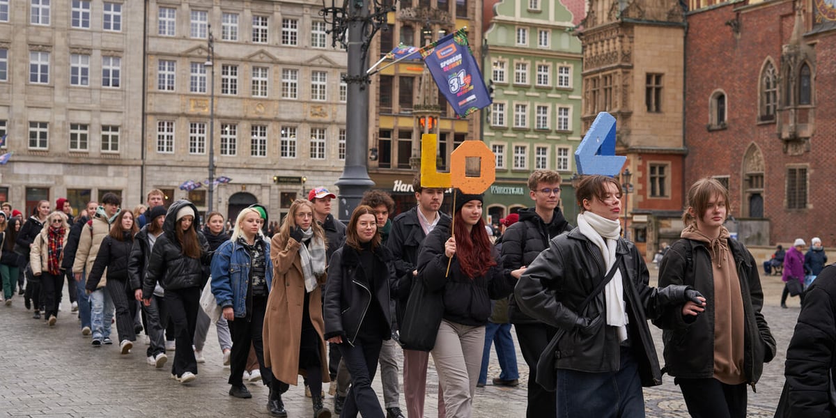 Korowód par tańczących Poloneza dla Fredry wokół Ryku (2023 rok). Uczniowie trzymają napis LO 4. 