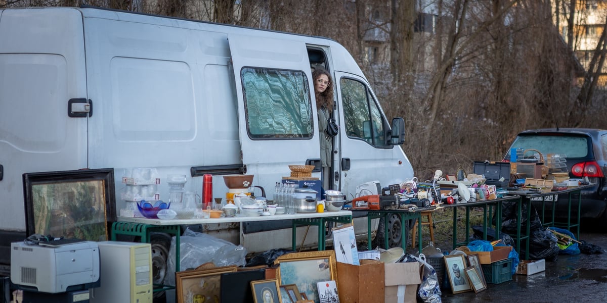 Targowisko na Świebodzkim - 4 lutego 2024. Na zdjęciu widać biały samochód, w drzwiach stoi kobieta. Koło auta są wystawione rzeczy na sprzedaż 