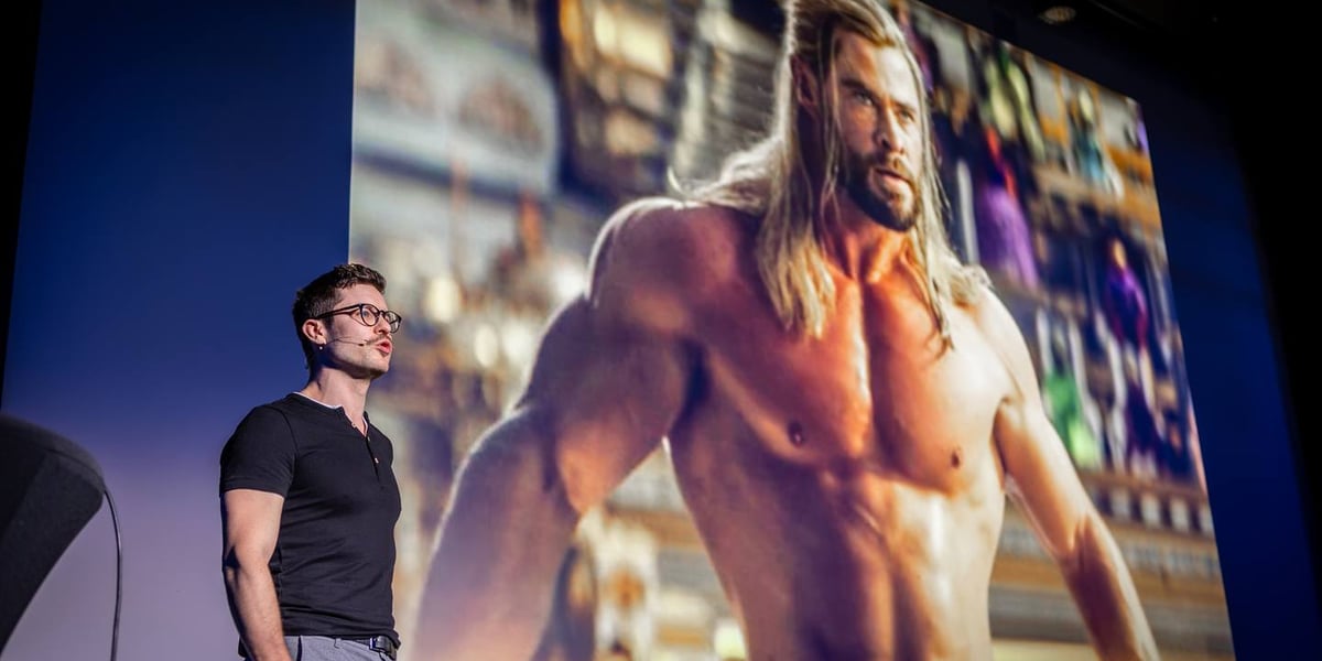 Na zdjęciu Maciej Kaselon opowiada o tym, że czujemy się jak bohaterowie, kiedy możemy poprawić czyjś językowy błąd, na slajdzie za nim filmowy Thor