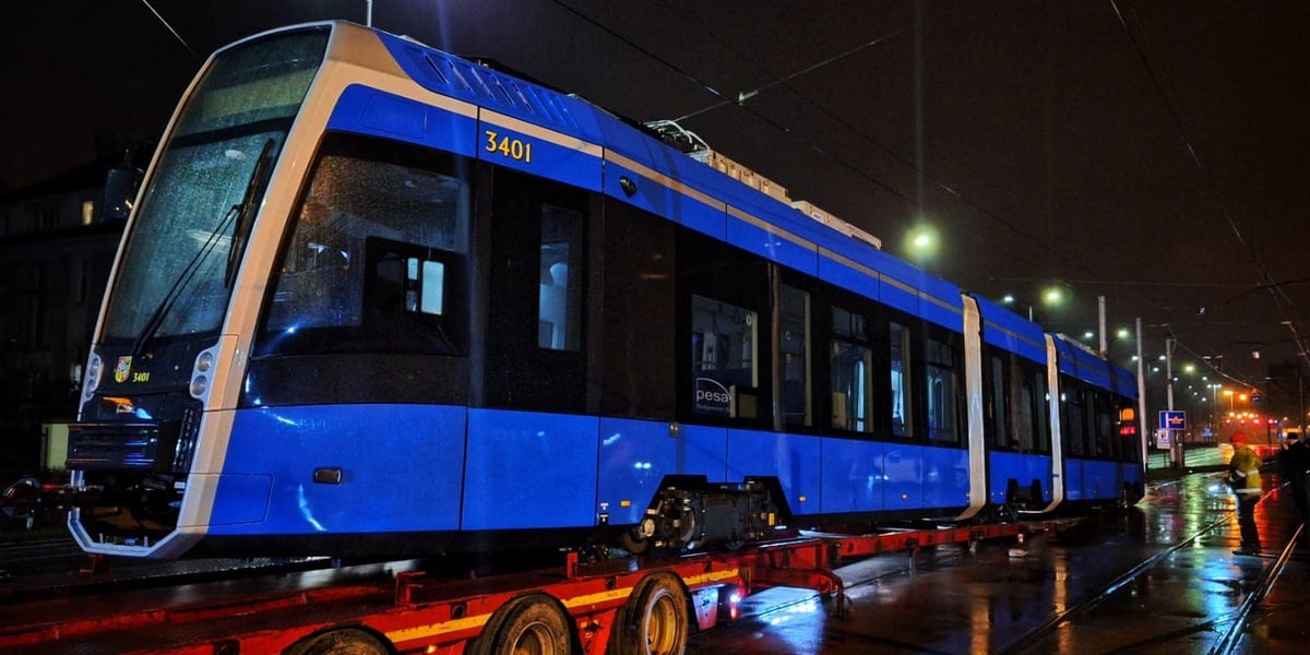 Zdjęcie miasta nocą, przejazd niebieskiego tramwaju na lawecie  