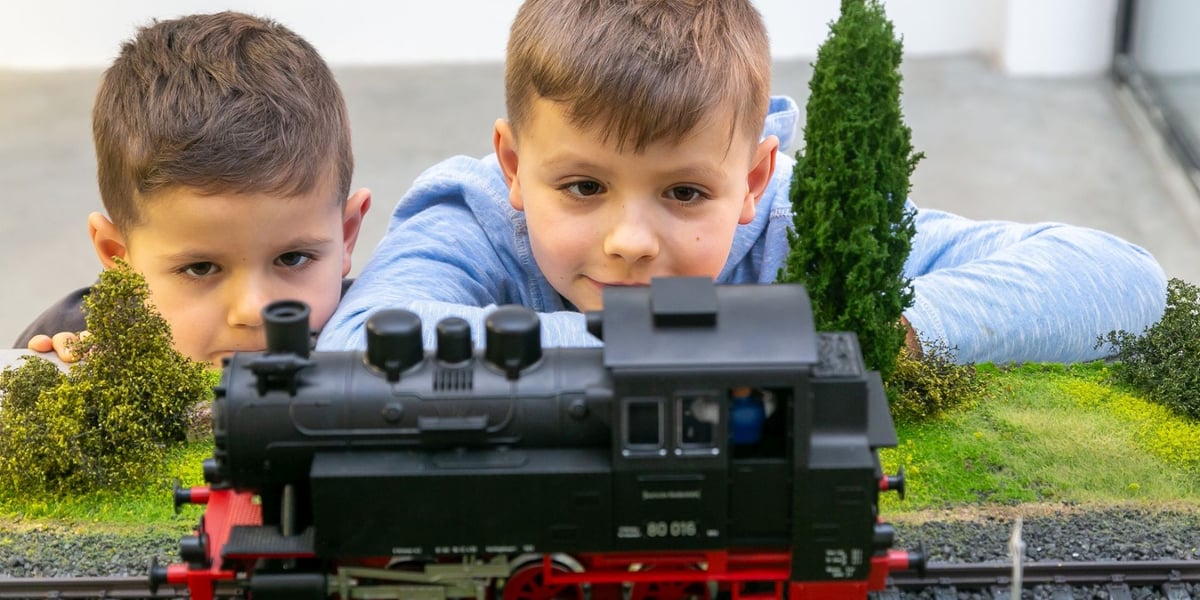 Dwóch chłopców patrzy na miniaturowy model pociągu w Modelarni Kolejkowo