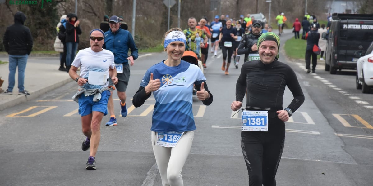 Zawodnicy na mecie Półmaratonu Ślężańskiego. Na pierwszym planie kobieta i po bokach dwóch mężczyzn