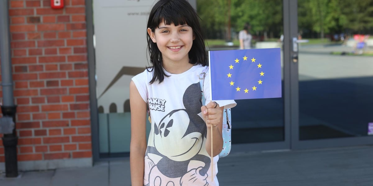 20 lat w Unii Europejskiej – radosne obchody podczas Majówki w Centrum Historii Zajezdnia. Na zdjęciu uśmiechnięta dziewczynka trzyma flagę Unii Europejskiej