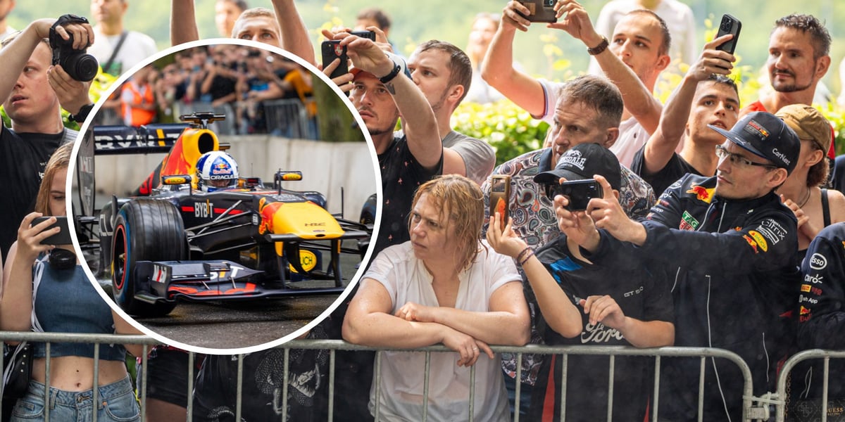 Kobiety, mężczyźni i dzieci patrzą na pojedynek bolidu F1