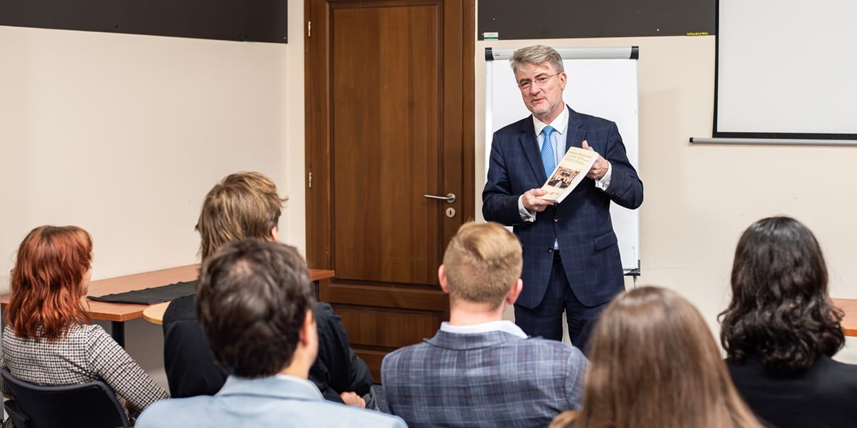 Dr Edward Wąsiewicz, Konsul Honorowy Republiki Austrii we Wrocławiu. Inauguracja Akademii Dyplomatycznej. Na zdjęciu elegancki mężczyzna przemawia przed grupą młodych osób w sali wykładowej