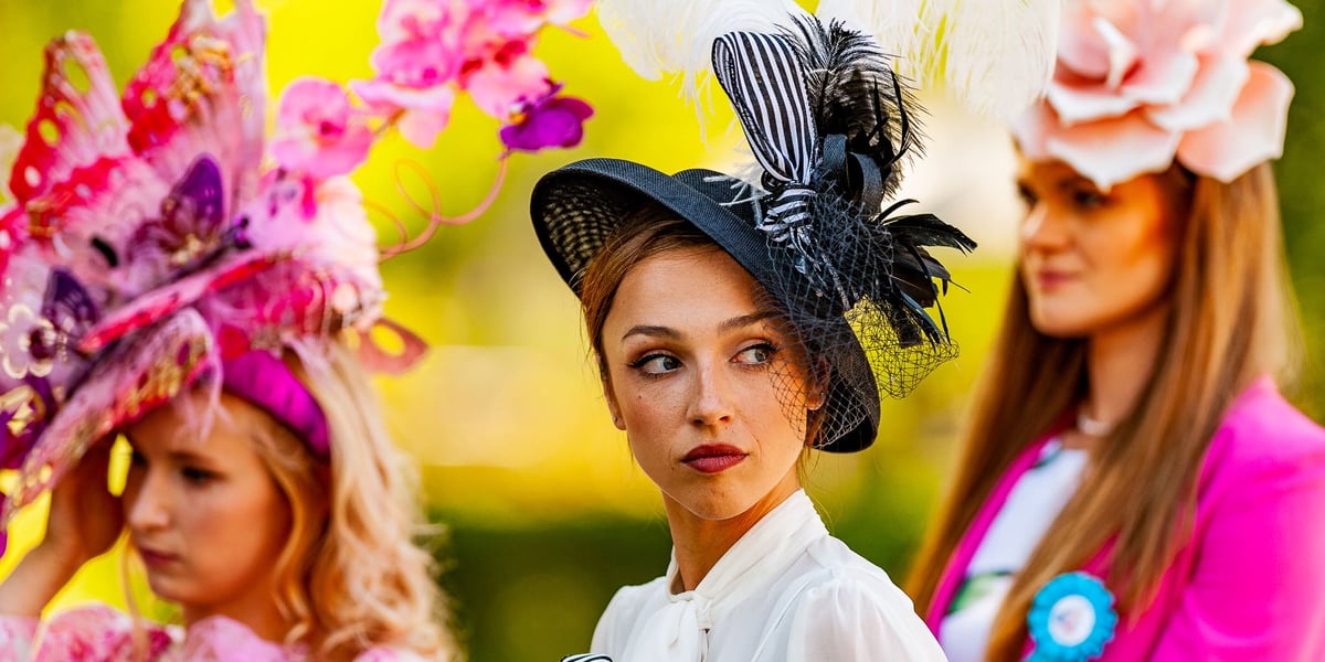 Trzy kobiety w elegenackich kreacjach i nakryciach głowy podczas Ladies Day na Partynicach w roku 2023