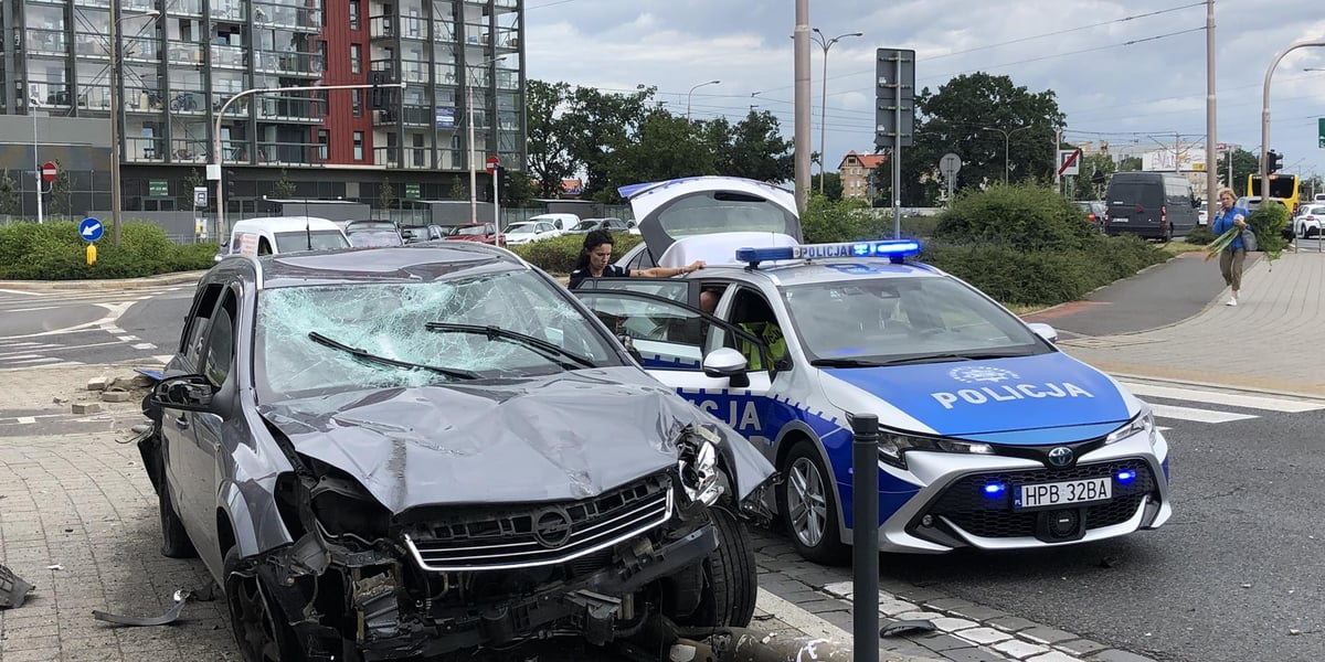 Rozbity samochód, obok stoi policjantka koło radiowozu 