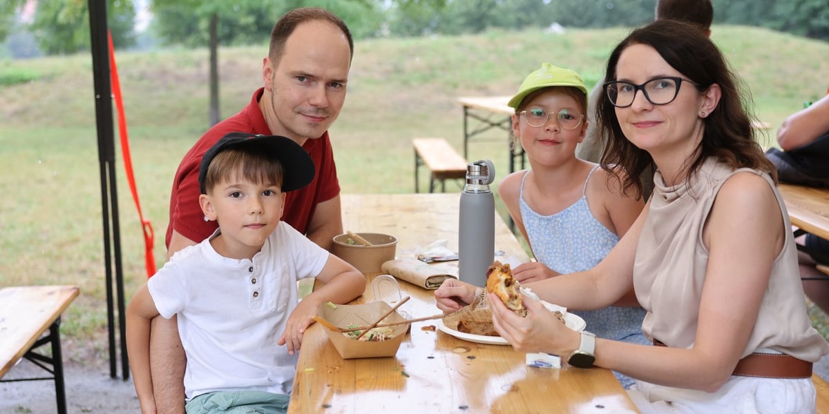 Gastro Miasto 2024 we Wrocławiu. Na zdjęciu mężczyzna, kobieta i dwójka dzieci - uczestnicy festiwalu, siedzą przy stole z jedzeniem 