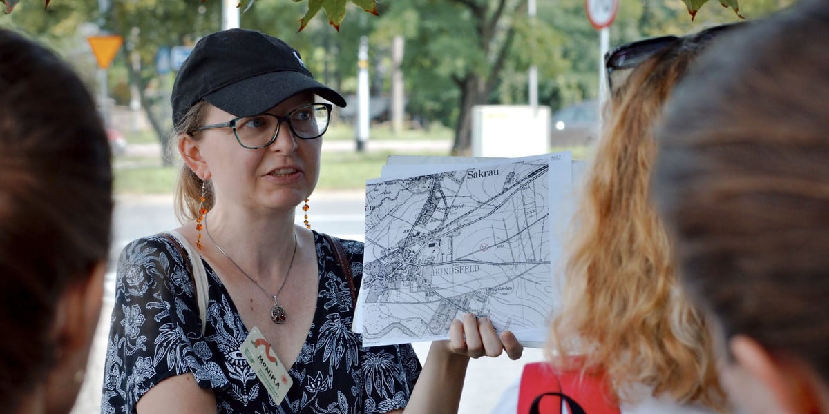 Kobieta w czapce z daszkiem trzyma w dłoni mapę. Spacer sąsiedzki po Psim Polu (18.08.2024), oprowadzają Monika Glińska i Zhanna Nogina