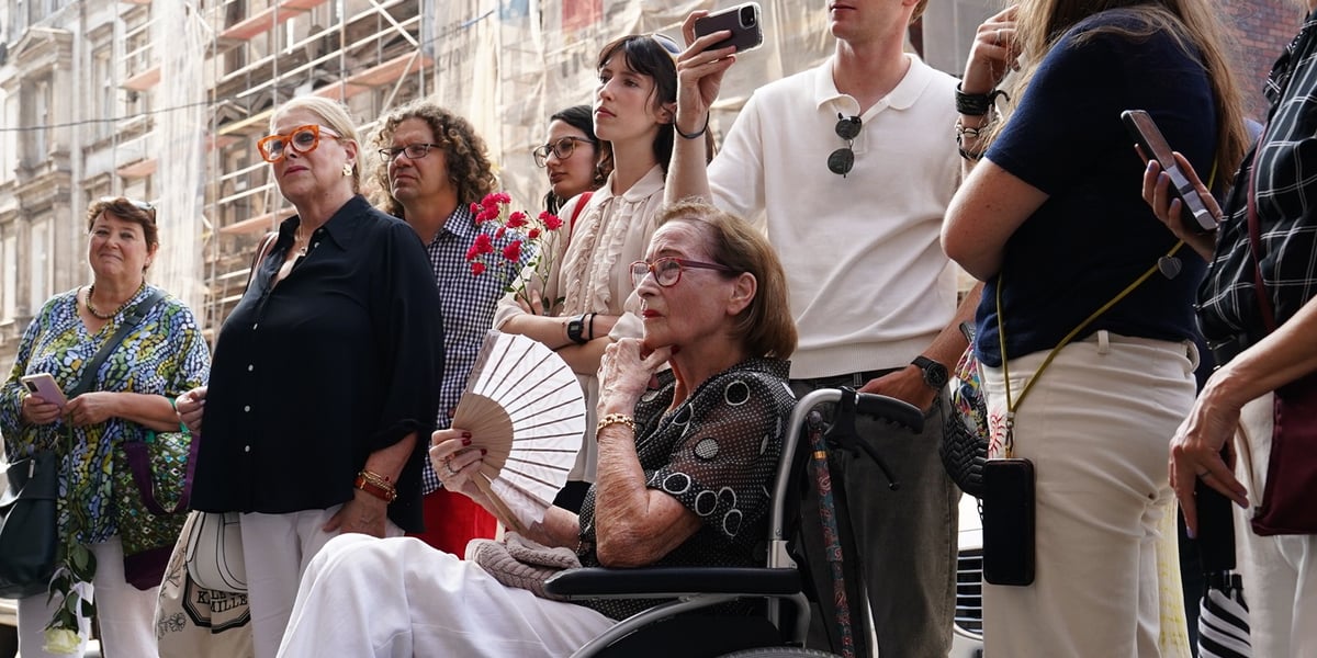 Kobieta na wózku inwalidzkim, obok kobiety i mężczyźni podczas uroczystości związanej z kamieniami pamięci Stolpersteine przy ul. Lelewela