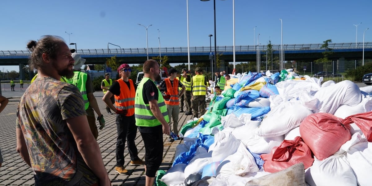 Mężczyzna niesie worek z piaskiem, w tle stadion Tarczyński Arena Wrocław