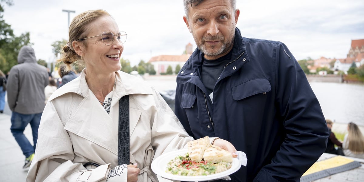 Finał Gastro Miasto na bulwarze Dunikowskiego - 28 września. Od lewej: uśmiechnięta kobieta w jasnym płaszczu pokazuje talerz z potrawą, obok mężczyzna w ciemnej kurtce.