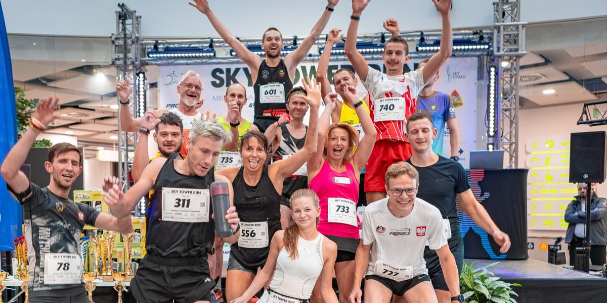 Grupa cieszących się biegaczy: mężczyźni i kobiety, którzy brali udział w Mistrzostwach Polski w bieganiu po schodach na Sky Tower. 19 października 2024