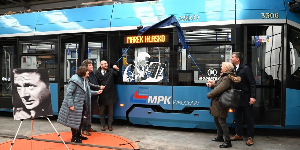 Kilka osób odsłania nazwisko Marka Hłaski na tramwaju w zajezdni przy ul. Ślężnej (22 listopada 2024)