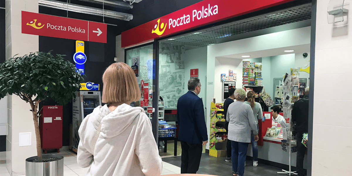 Kobiety i mężczyźni w kolejce na Poczcie Polskiej 