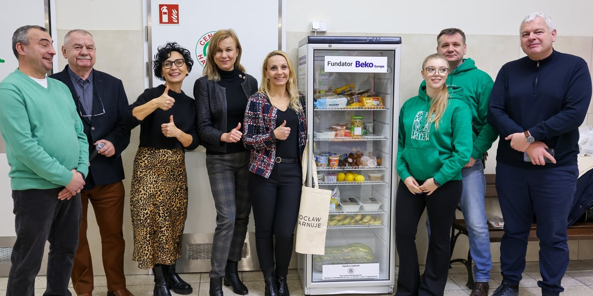 Grupa ludzi na tle nowej lodówki społecznej w centrum handlowym "Gaj".