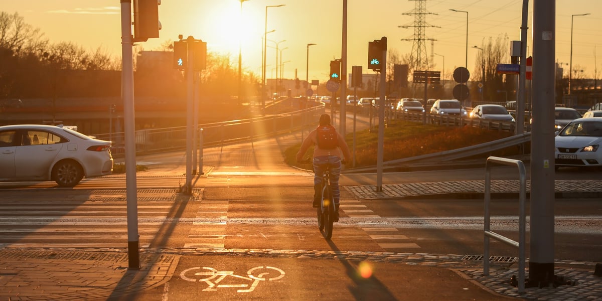 Na alei Wielkiej Wyspy wszystkie drogi rowerowe i chodniki są już gotowe. Na zdjęciu rowerzysta w blasku zachodzącego słońca 