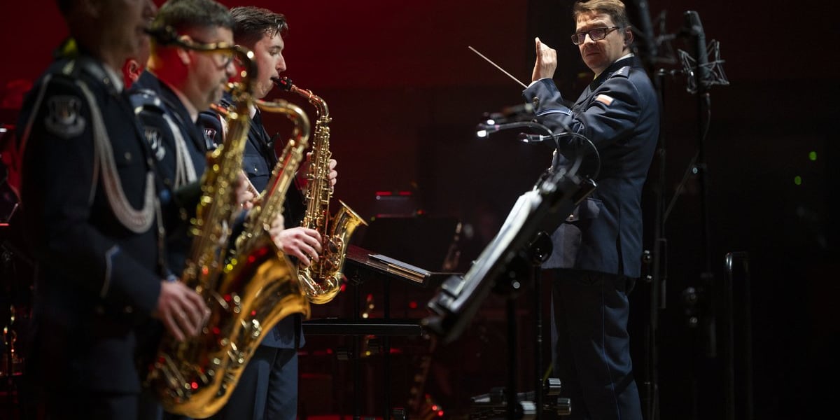 Koncert jubileuszowy Orkiestry Komendy Wojewódzkiej Policji we Wrocławiu w Narodowym Forum Muzyki we Wrocławiu. Na zdjęciu dyrygent oraz trzech saksofonistów podczas koncertu, wszyscy są w policyjnych mundurach