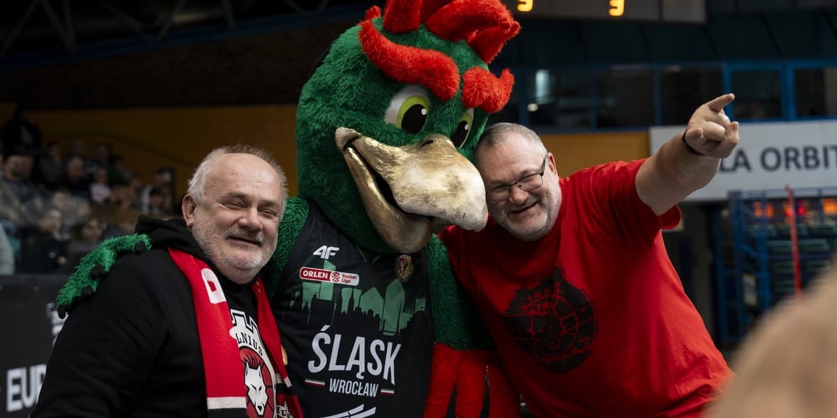 Mężczyźni i maskotka Śląska na trybunie Orbity podczas meczu Śląska z Rytasem