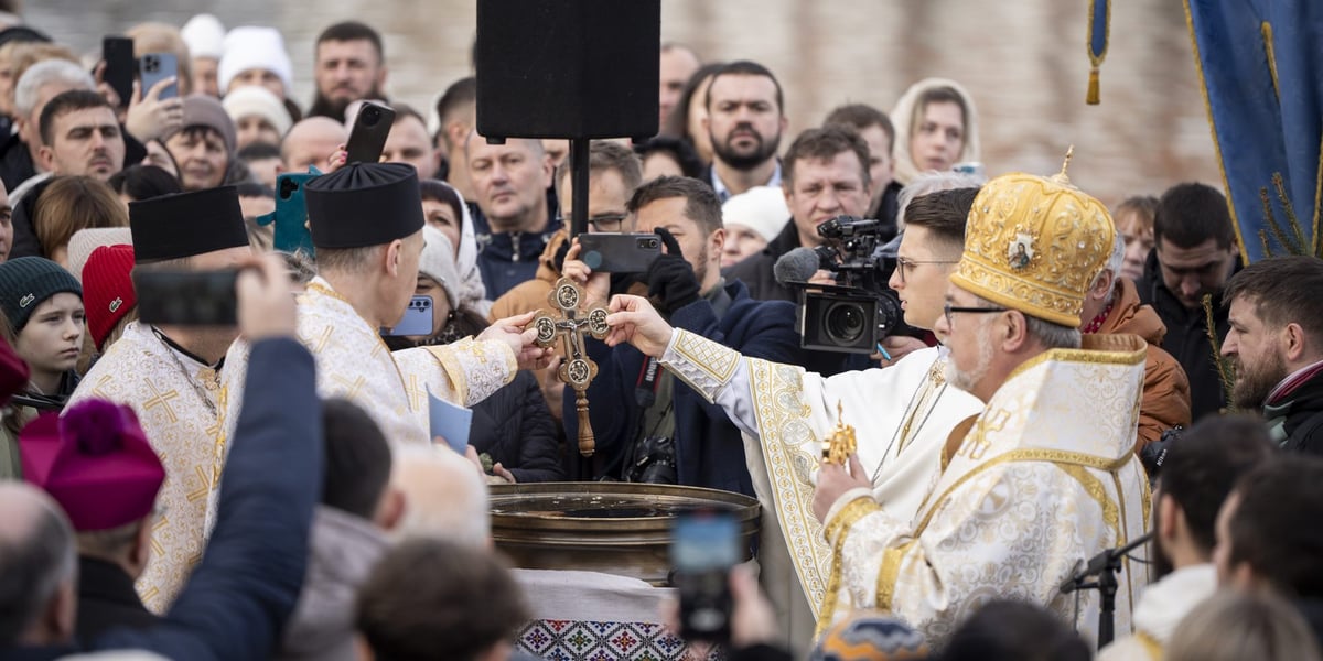 Duchowni trzymają krzyż nad naczyniem z wodą, wokół stoją wierni zgromadzeni nad Odrą na święcie Jordanu (6 stycznia) w dniu Objawienia Pańskiego
