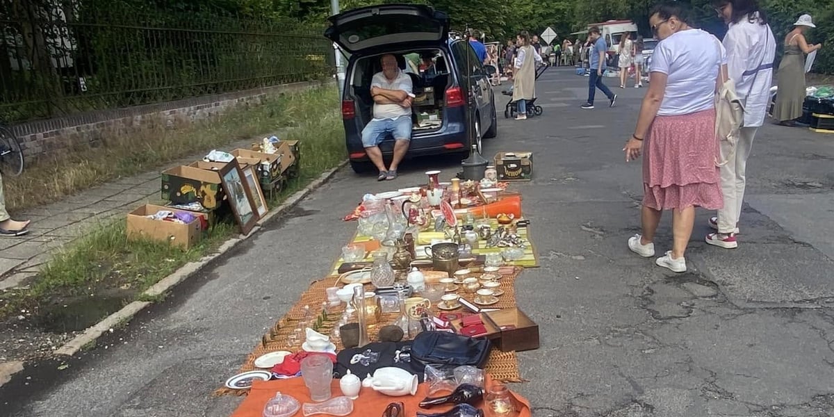 Pchli targ na Kasztanowej. Na zdjęciu widać przedmioty rozłożone na matach na ulicy oraz przechodzących ludzi