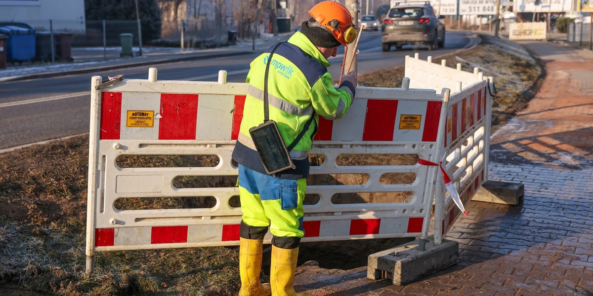 Awaria na Strachocińskiej dobiegła końca, na zdjęciu mężczyzna ustawia barierki odgradzające miejsce awarii
