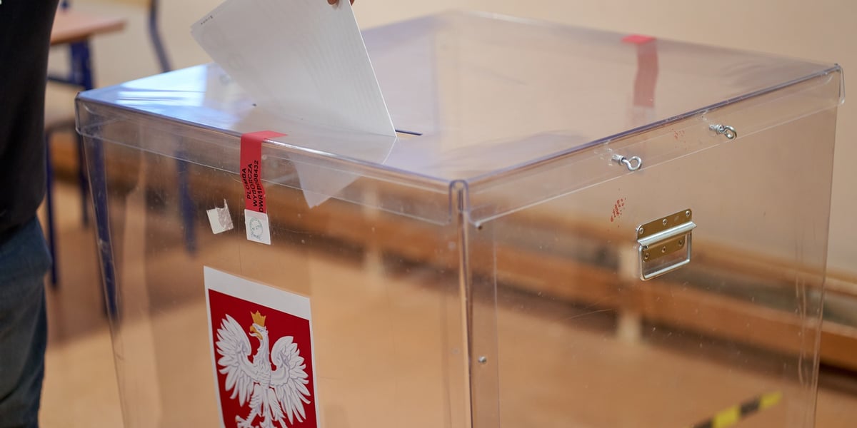 Na zdjęciu urna do głosowania i osoba wrzucająca karty do głosowania. Zdjęcie ilustracyjne