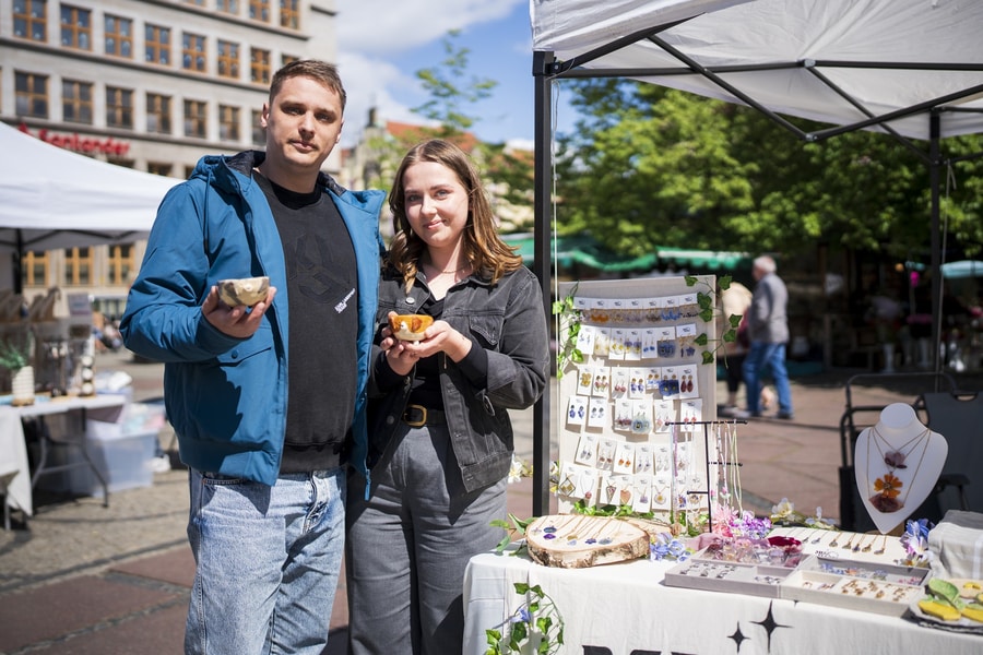 Kobieta i mężczyzna stoją obok siebie na placu Solnym i pokazują produkty kupione na bazarze rękodzieła