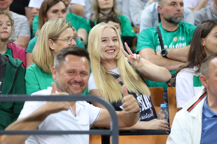 Uśmiechnięta kobieta i inny kibice na trybunie Hali Stulecia na meczu Śląska z Górnikiem