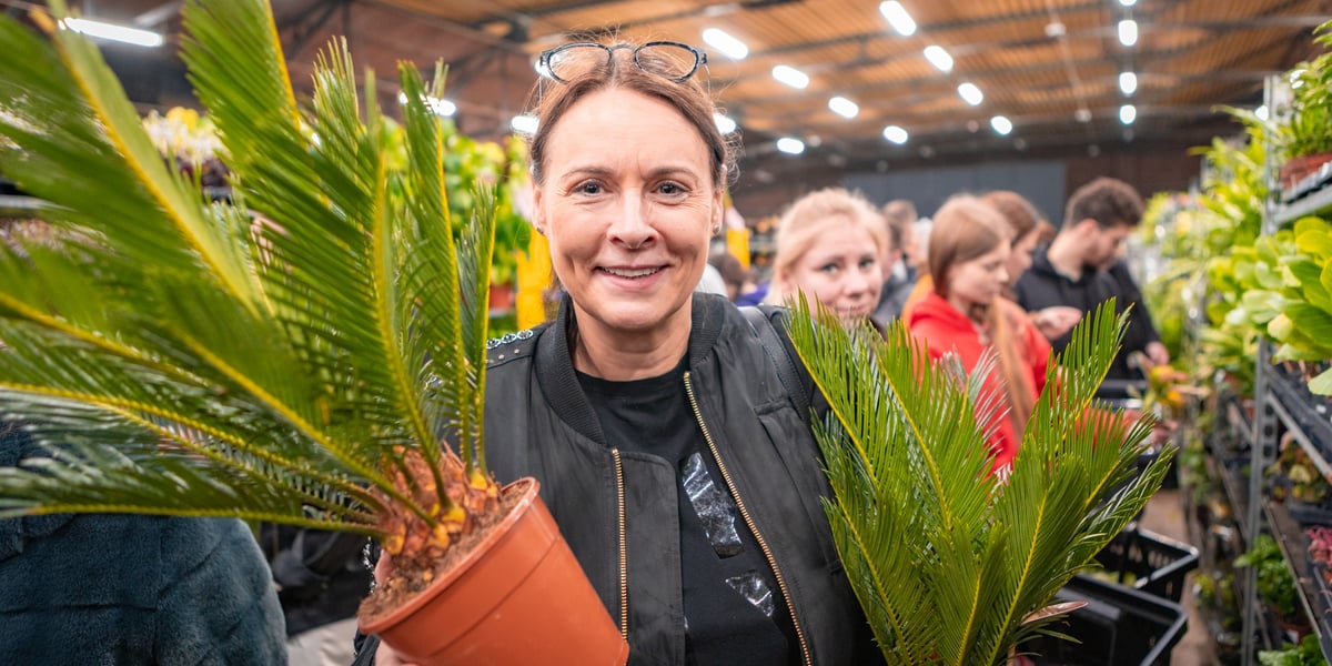 Festiwal Roślin w Czasoprzestrzeni we Wrocławiu. Na zdjęciu uśmiechnięta kobieta z kwiatem doniczkowym