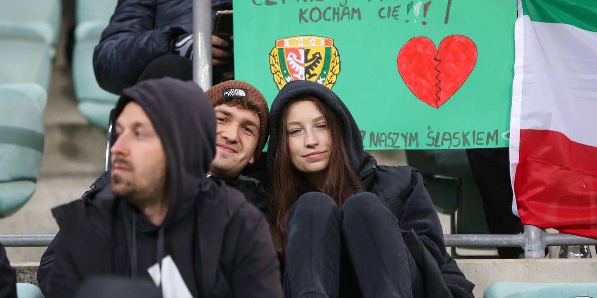 Kibice z transparentem, na którym napisano: "czy wygrywasz, czy nie, ja i tak kocham cię"