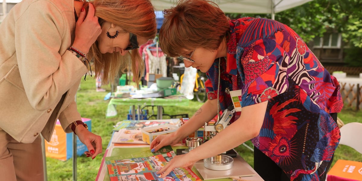 Dwie kobiety pochylają się nad stolikiem z materiałami edukacyjnymi