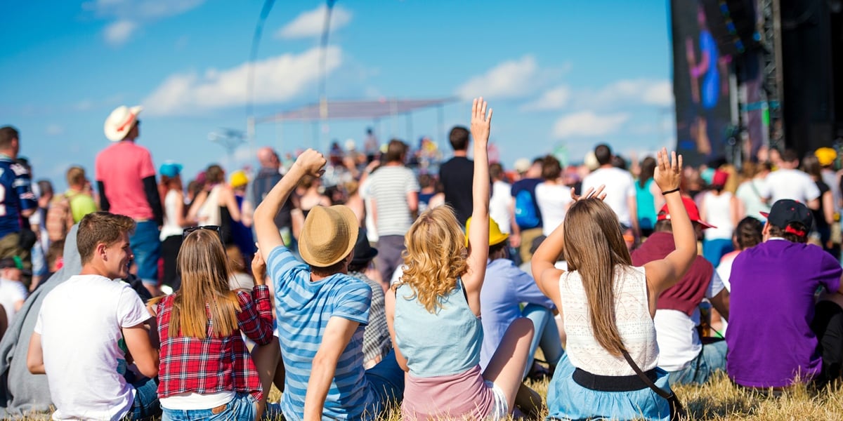 Na zdjęciu koncert w plenerze, widać rozbawionych ludzi siedzących na trawie
