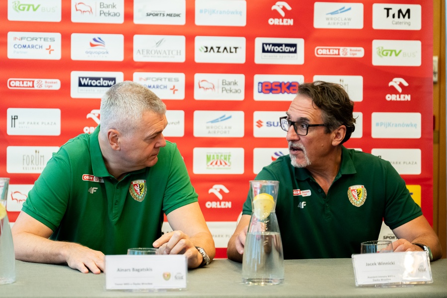 Trener Ainars Bagatskis (po lewej) i asystent Jacek Winnicki (po prawej) przy stole na konferencji prasowej