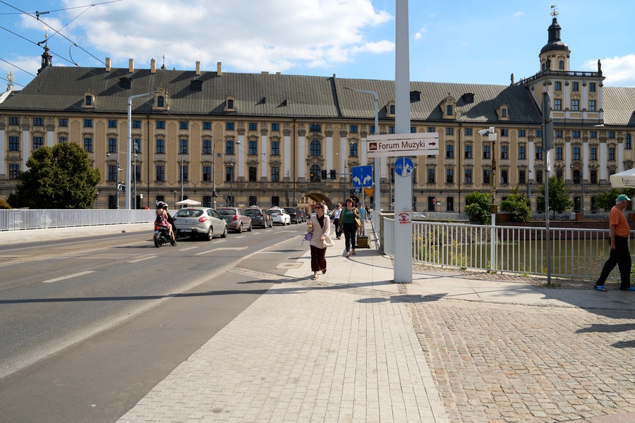 Widok na most Uniwersytecki i gmach główny UWr, na moście piesi i auto (19 sierpnia 2025)