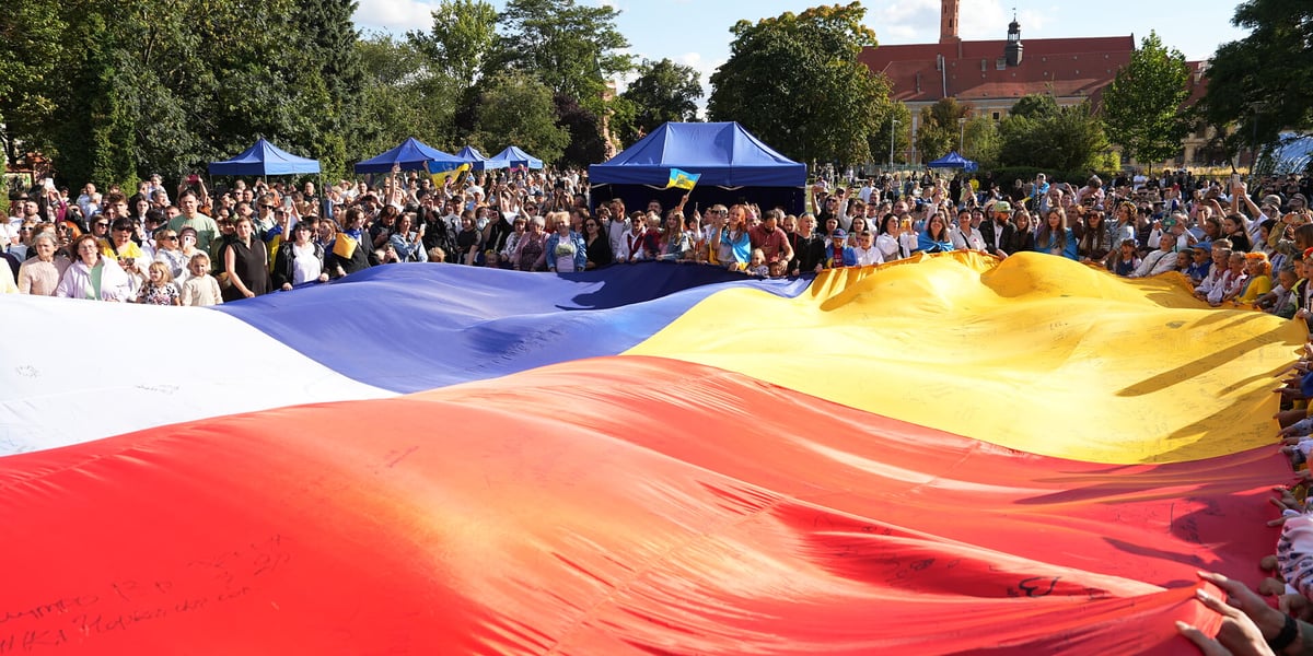 Flagi Polska i Ukraińska trzymane przez tłum stojących w koło ludzi