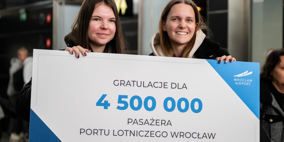 Dwie przyjaciółki z Poznania trzymające tablicę gratulacyjną z okazji rekordu frekwencji na lotnisku we Wrocławiu (Aleksandra po prawej stronie)