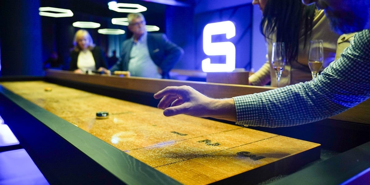 Gracze przy stole do shuffleboarda, wieczór zapowiadający otwarcie Sky Games