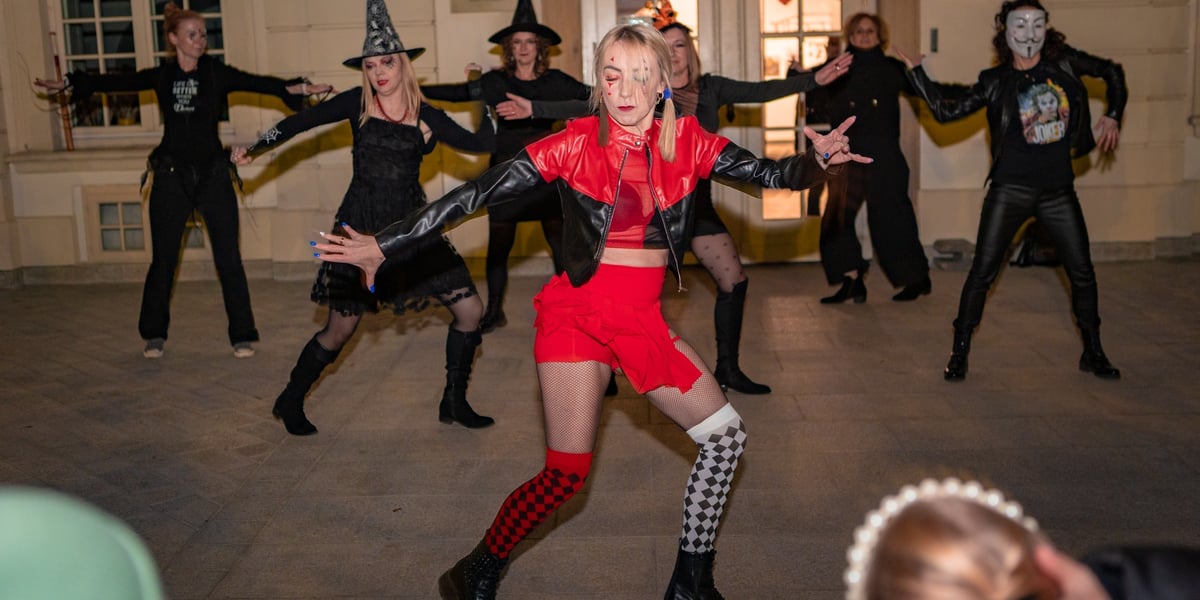 Grupa ludzi przebrana za czarownice i duchy tańczy przed zamkiem. Halloween w OPT Leśnica.