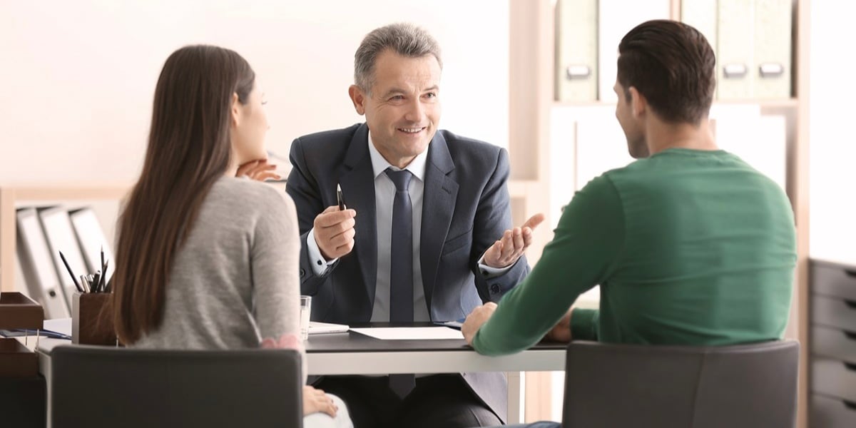 Na zdjęciu elegancki mężczyzna rozmawia w biurze z dwiema osobami. Zdjęcie ilustracyjne